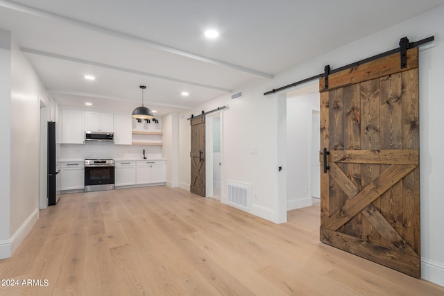 unfurnished living room featuring sink, light wood-type flooring, beam ceiling, and a barn door