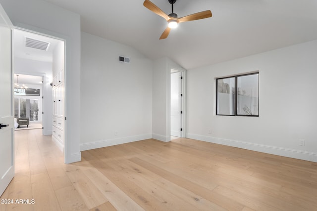 unfurnished room featuring ceiling fan with notable chandelier, light hardwood / wood-style flooring, and vaulted ceiling