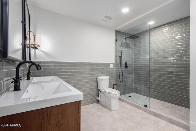 bathroom featuring tile walls, tiled shower, vanity, toilet, and tile patterned floors