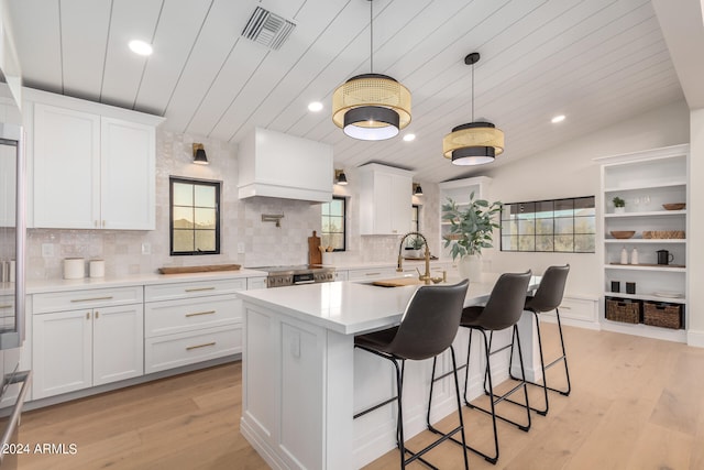 kitchen with white cabinets, lofted ceiling, light wood-type flooring, and sink