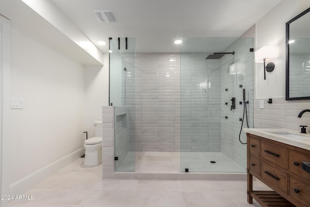 bathroom featuring tile patterned flooring, vanity, toilet, and a shower with shower door