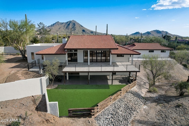 rear view of property featuring a lawn, a mountain view, and a patio area