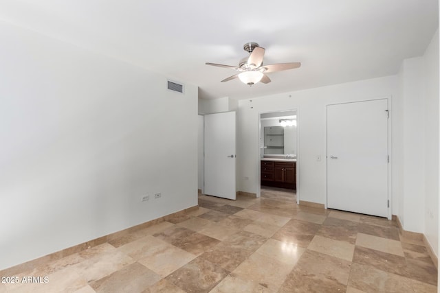unfurnished bedroom featuring ensuite bathroom, a sink, baseboards, and ceiling fan