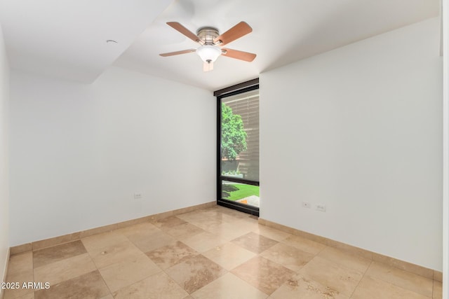 spare room with a wall of windows, baseboards, and a ceiling fan
