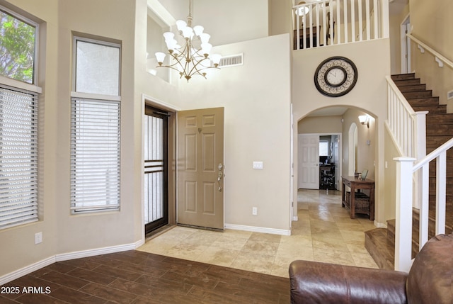 foyer entrance with visible vents, arched walkways, a high ceiling, and stairway