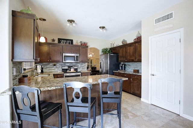 kitchen with dark brown cabinetry, visible vents, appliances with stainless steel finishes, a sink, and a peninsula