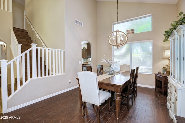 dining room with baseboards, a high ceiling, arched walkways, and dark wood-type flooring