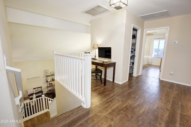 corridor with baseboards, an upstairs landing, wood finished floors, and visible vents