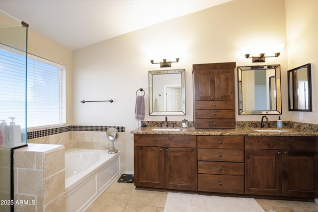 full bath featuring a sink, a garden tub, double vanity, and lofted ceiling