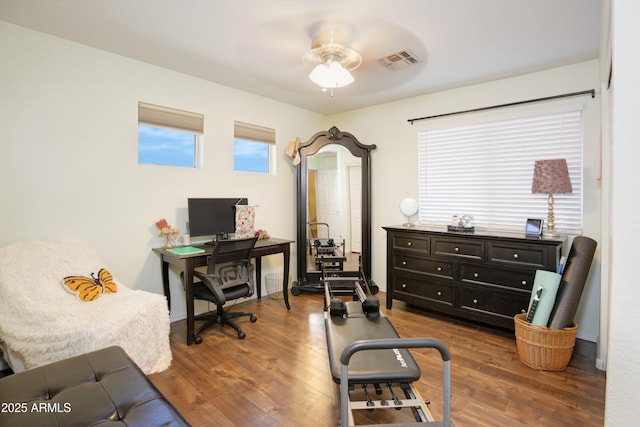 home office with a ceiling fan, wood finished floors, and visible vents