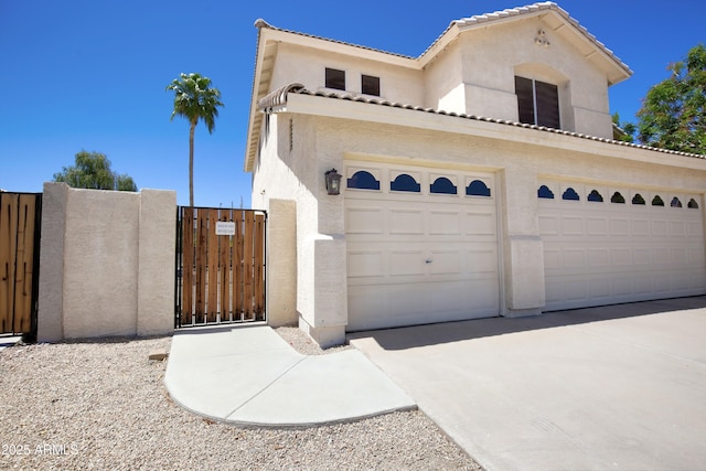 view of front of property with a garage, stucco siding, a gate, concrete driveway, and a tile roof