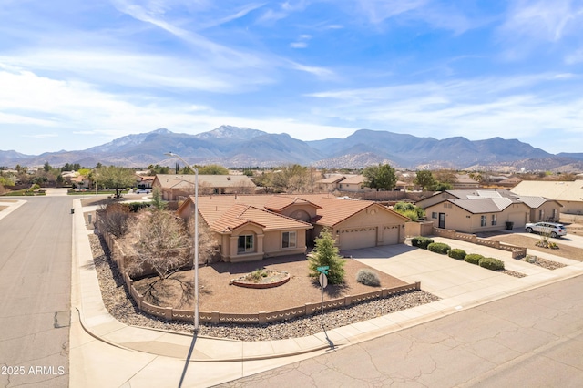 view of front facade featuring an attached garage, a residential view, a tiled roof, driveway, and a mountain view