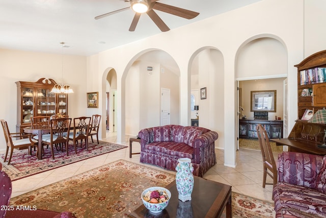 tiled living area featuring a high ceiling and ceiling fan with notable chandelier