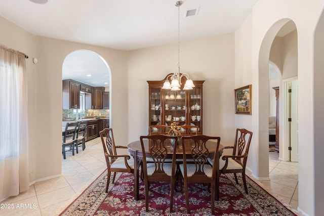 dining space featuring light tile patterned flooring, visible vents, baseboards, and a notable chandelier