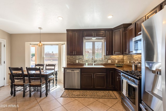 kitchen with dark countertops, dark brown cabinets, decorative backsplash, appliances with stainless steel finishes, and a sink