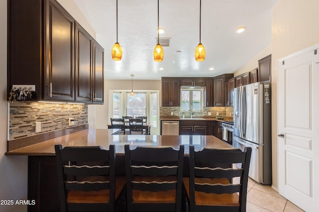 kitchen featuring visible vents, dark brown cabinets, backsplash, light tile patterned floors, and stainless steel appliances