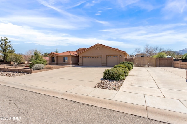 view of front of home with stucco siding, a gate, fence, concrete driveway, and an attached garage