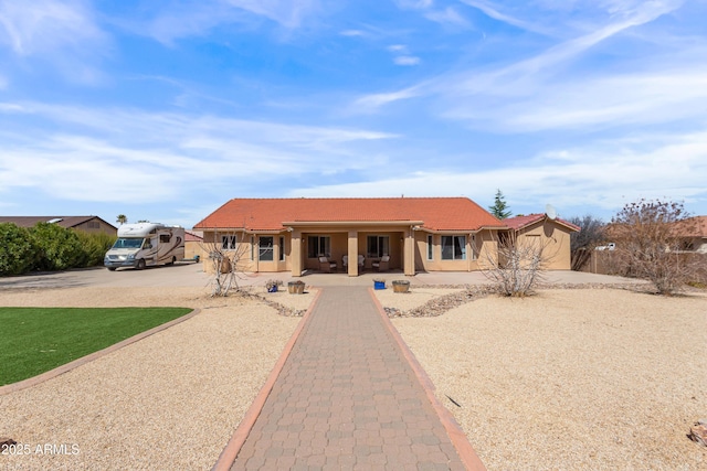 ranch-style home with a tiled roof, driveway, and stucco siding