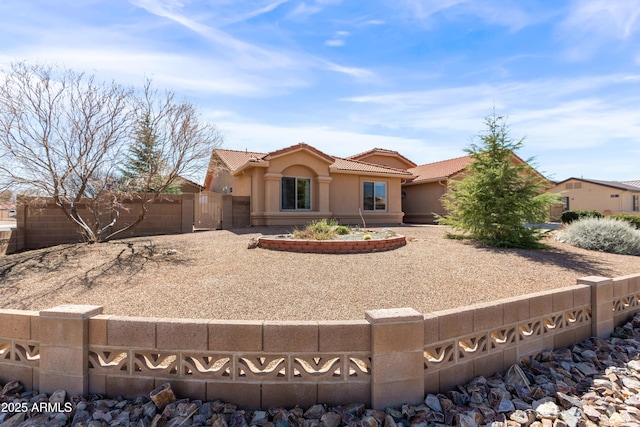 view of front facade featuring a tile roof, a gate, fence, and stucco siding