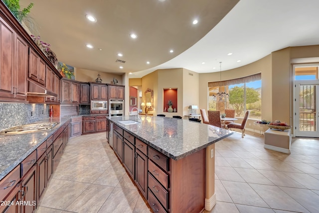 kitchen with backsplash, dark stone counters, sink, appliances with stainless steel finishes, and a large island