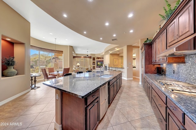 kitchen featuring tasteful backsplash, a spacious island, sink, dark stone countertops, and light tile patterned flooring