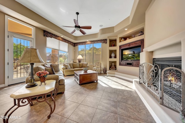 tiled living room with built in shelves, a wealth of natural light, and ceiling fan