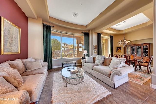 tiled living room featuring a tray ceiling and an inviting chandelier