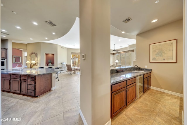 kitchen featuring oven, kitchen peninsula, sink, and dark stone counters