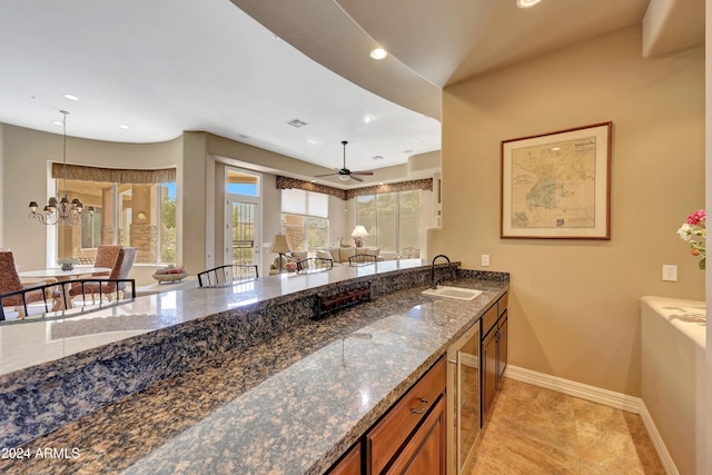 kitchen with sink, wine cooler, ceiling fan, and dark stone countertops