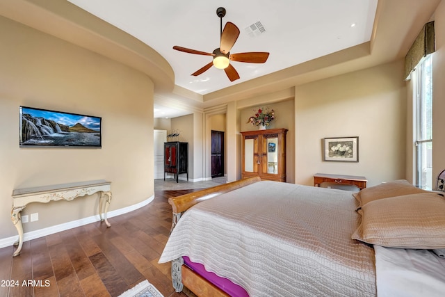 bedroom featuring a raised ceiling, ceiling fan, and dark hardwood / wood-style floors