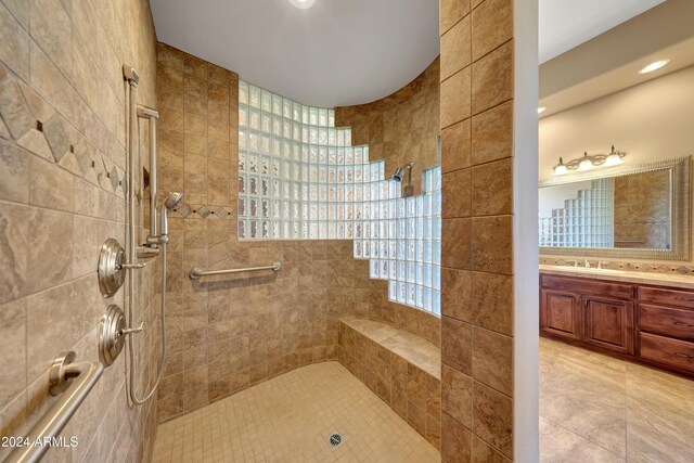 bathroom with a tile shower, vanity, and tile patterned floors