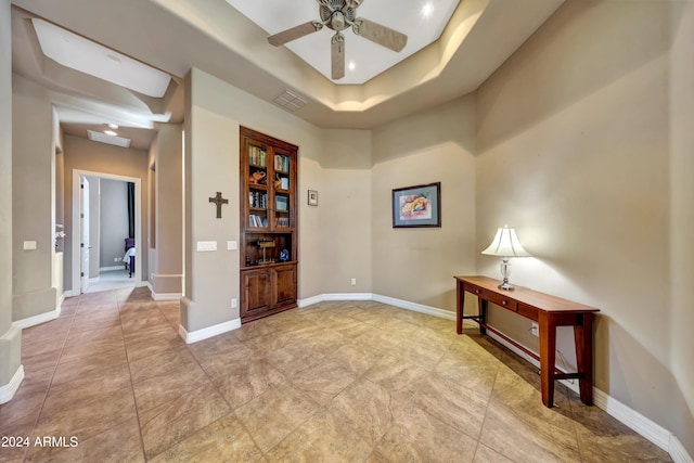 empty room with ceiling fan and a raised ceiling