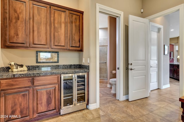 kitchen featuring light tile patterned flooring, beverage cooler, and sink