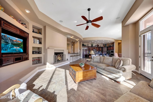 living room featuring tile patterned floors, built in features, plenty of natural light, and ceiling fan