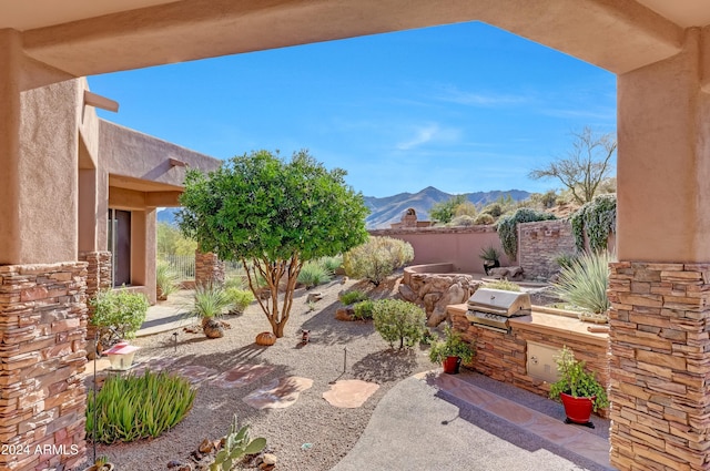 view of patio with a grill, a mountain view, and an outdoor kitchen