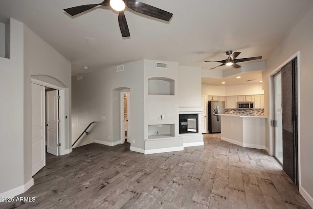 8180 E Shea Blvd Unit 1075, Scottsdale, AZ 85260 - unfurnished living room with ceiling fan, light wood finished floors, arched walkways, baseboards, and recessed lighting