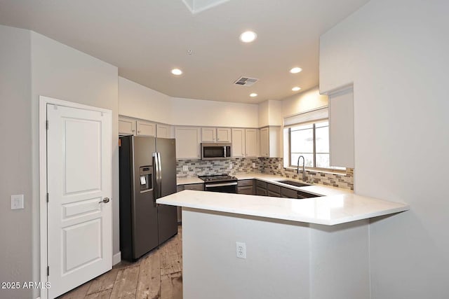 8180 E Shea Blvd Unit 1075, Scottsdale, AZ 85260 - kitchen with stainless steel appliances, a sink, a peninsula, light countertops, and tasteful backsplash