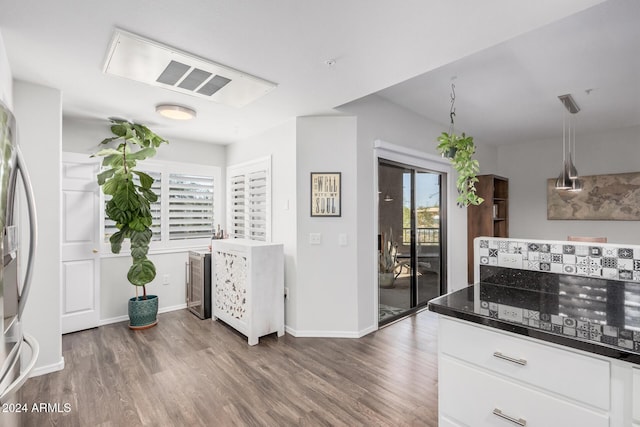 kitchen with stainless steel fridge, dark hardwood / wood-style flooring, decorative light fixtures, and white cabinetry