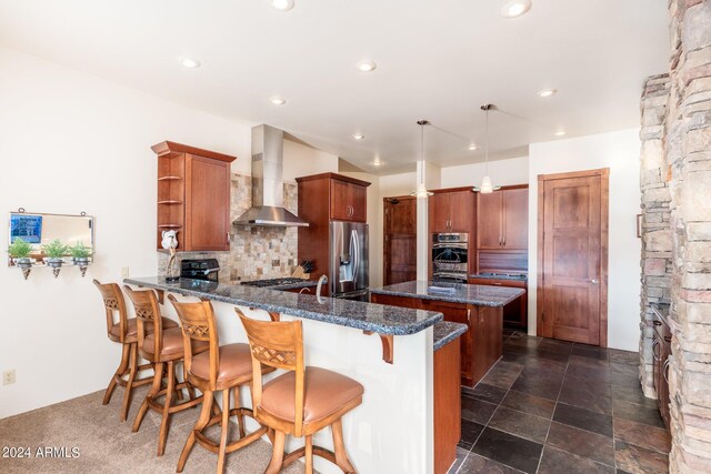 kitchen featuring stainless steel appliances, wall chimney exhaust hood, pendant lighting, tasteful backsplash, and a breakfast bar