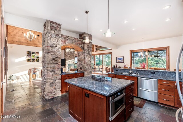 kitchen featuring plenty of natural light, a center island, stainless steel appliances, and dark stone counters