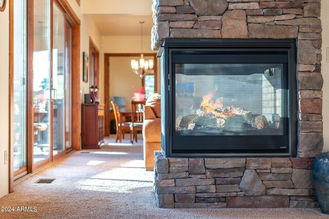 room details featuring a fireplace, an inviting chandelier, and carpet floors