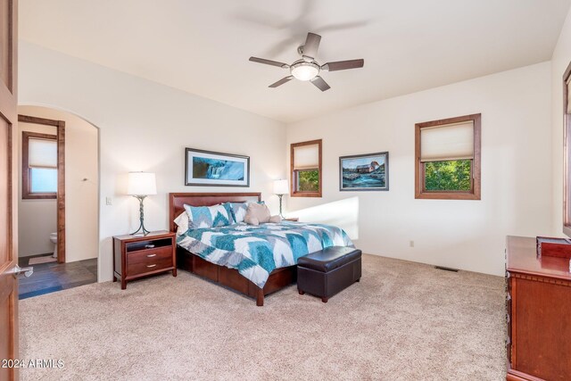 carpeted bedroom featuring ceiling fan and ensuite bath