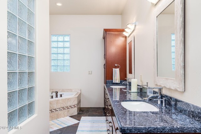 bathroom featuring vanity, tile patterned flooring, and tiled bath