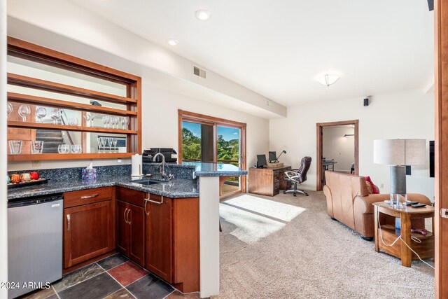 kitchen featuring dark stone counters, dark carpet, kitchen peninsula, sink, and stainless steel dishwasher