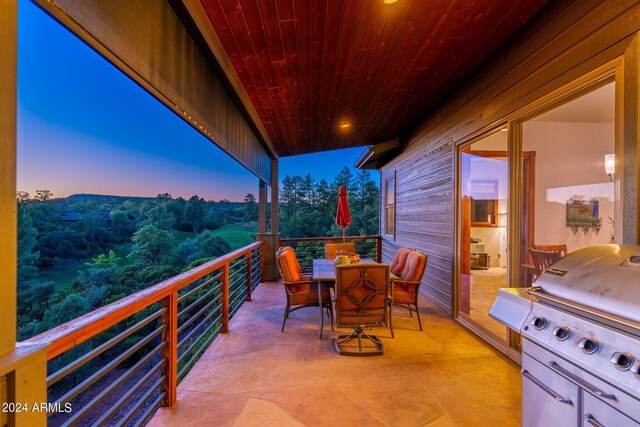 patio terrace at dusk with area for grilling and a balcony