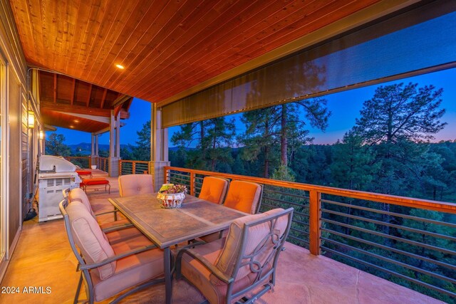 patio terrace at dusk featuring a grill and exterior kitchen