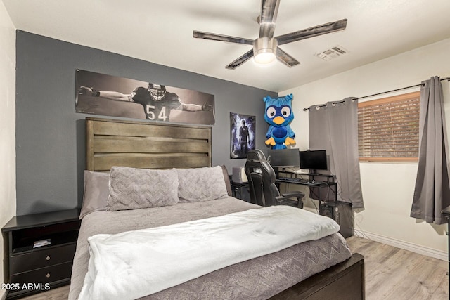 bedroom with a ceiling fan, wood finished floors, visible vents, and baseboards