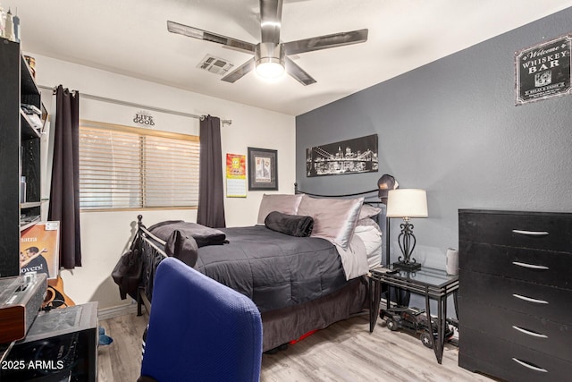 bedroom with a ceiling fan, visible vents, and wood finished floors