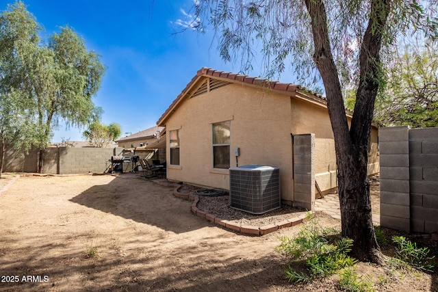 back of house with a patio area, a fenced backyard, central AC, and stucco siding