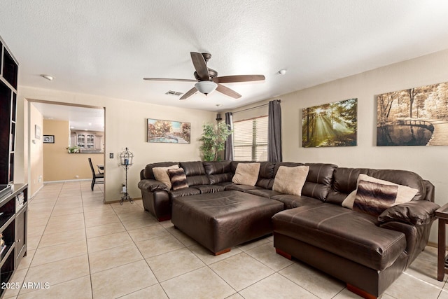 living room featuring a ceiling fan, visible vents, a textured ceiling, and light tile patterned floors